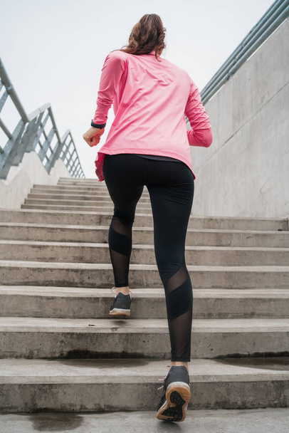 Portrait of a sport woman running on stairs outdoors. Fitness, sport and healthy lifestyle concepts. - 写真・画像