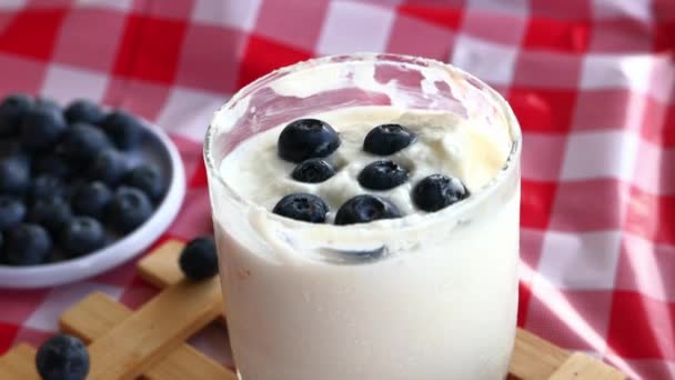 Sluiten van blauwe bes op yoghurt op tafel  - Video