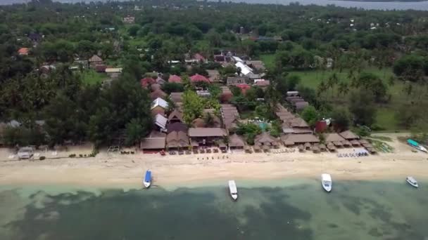 Gili Air, Індонезія: зйомки острова з дроном dji saprk. У рамі острова, в районі пляжу, транспортні човни пришвартовані біля узбережжя. Панорамний вид. Неспокійна погода.  - Кадри, відео
