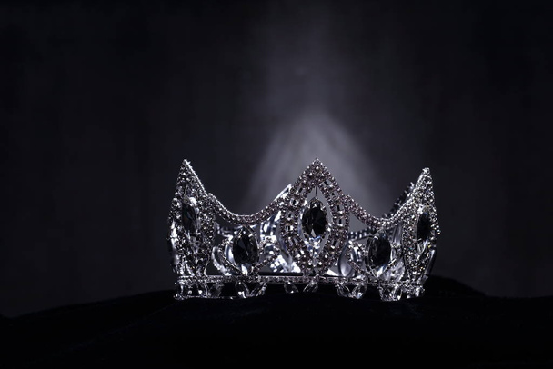 Diamond Silver Crown for Miss Pageant Beauty Contest, Crystal Tiara jewelry decorated gems stone and abstract dark background on black velvet fabric cloth, Macro photography copy space for text logo - 写真・画像
