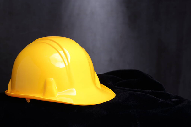 Желтая каска для инженера-строителя на черной бархатной ткани, студийное освещение на абстрактном темном фоне, пространство для копирования текста логотипа
 - Фото, изображение