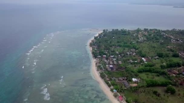 Gili Air, Endonezya: İnsansız hava aracı ile bir adanın vurulması. Adanın çerçevesinde, sahil bölgesinde, kıyıya demir atmış nakliye gemileri. Panoramik görüntüler. Bulutlu hava.  - Video, Çekim