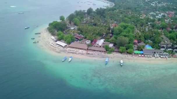 Gili Air, Endonezya: İnsansız hava aracı ile bir adanın vurulması. Adanın çerçevesinde, sahil bölgesinde, kıyıya demir atmış nakliye gemileri. Panoramik görüntüler. Bulutlu hava.  - Video, Çekim
