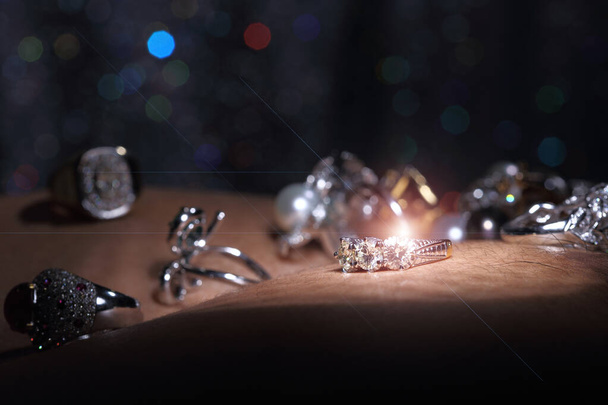 Edelstenen, sieraden, Daimond, goud zilver, robijn vavluable ringen gepresenteerd op menselijke huid over donkere bokeh achtergrond met glanzend object - Foto, afbeelding