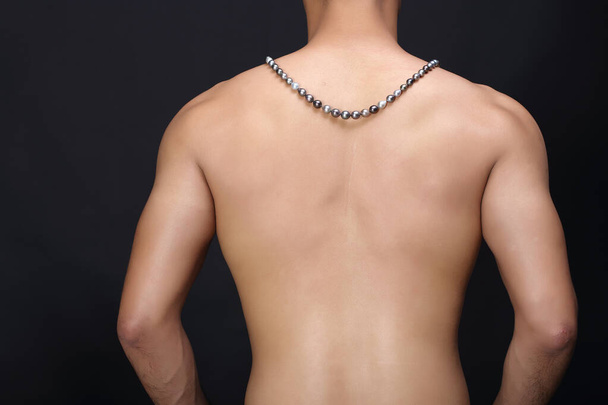 Gems, Jewelry, Diamond, Gold Pedant hang over muscle back of male model, dark background - Fotó, kép