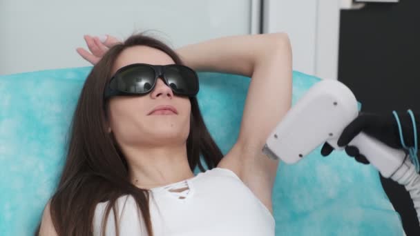Ładna dziewczyna otrzymuje laserowe usuwanie włosów pachy w studiu piękności - Materiał filmowy, wideo