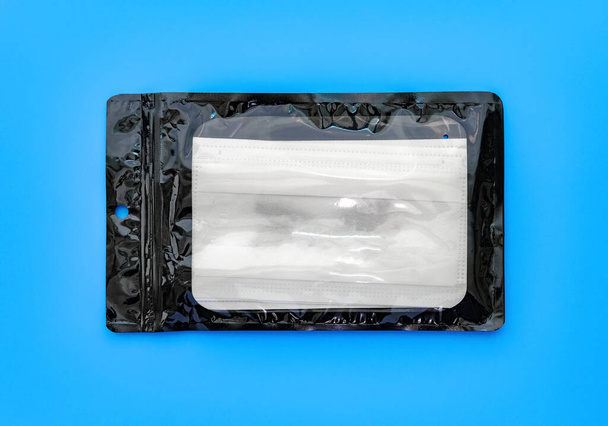 pack of disposable medical face masks on blue background - Фото, изображение