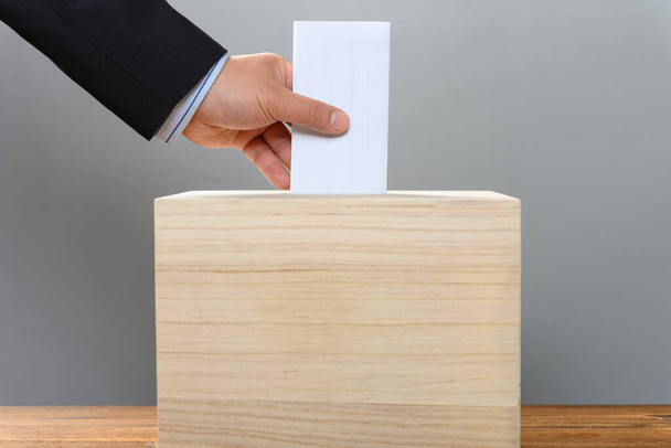 Mann steckt sein Ticket in eine Wahlurne - Foto, Bild