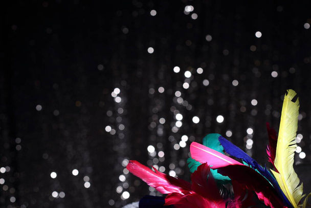 Plume d'oiseau coloré sur la vague de tissu de fourrure avec fond de bulle de bokeh de paillettes texturées, espace de copie publicitaire pour le logo texte salutation, félicitations, vacances, bijoux et concept de luxe - Photo, image