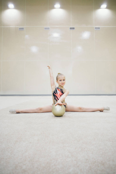 A girl in a tracksuit doing exercises with ball on a white background. Healthy lifestyle concept, sports uniforms, world Cup, gym, specialized clothing, uniforms - Φωτογραφία, εικόνα