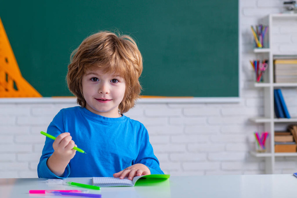 Primary school pupil. Children learning. Cute child boy in classroom near blackboard desk. Chalkboard copy space. - Foto, immagini