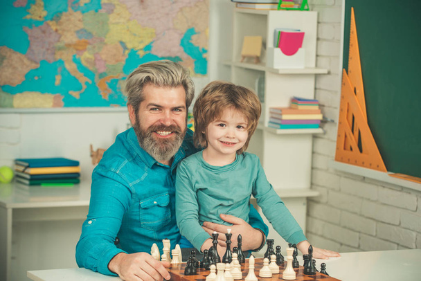 Teacher and schoolboy playing chess in class. Happy two generations of men have fun and playing Chess. Father and son. - Foto, Imagen