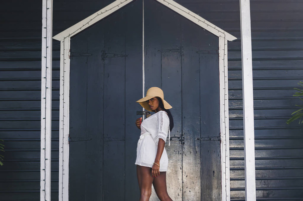 Černá žena ve věku 25 až 30 let, před kostelními dveřmi, oblečená v bílém modelingu, svěžím letním a tropickém oblečení. - Fotografie, Obrázek