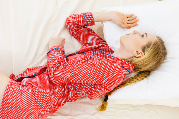 Relax rest sleep positions concept. Girl drowning in dreams. Young woman wearing red dotted pajamas lying in bed on the side dreaming deeply. - Foto, Bild