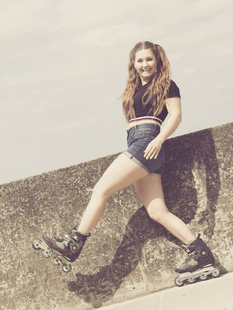 Young woman wearing roller skates outdoor. Fashionable fit girl having fun at sunny summer day. - Foto, afbeelding
