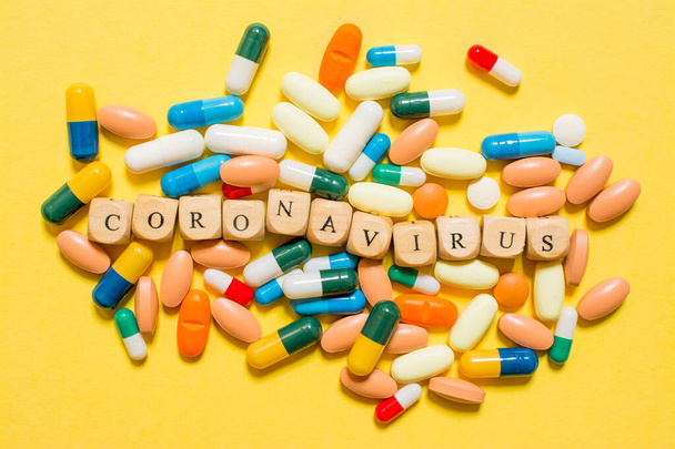 the word Coronavirus, text made with dice and pills on yellow background - Fotografie, Obrázek