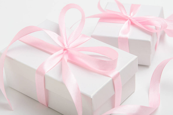 Un regalo para una mujer en una caja blanca con una cinta rosa. Felicitaciones por la fiesta, el día de la mujer
 - Foto, imagen