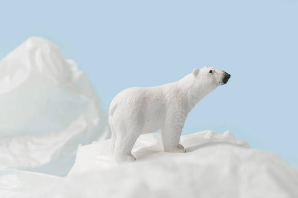 weißer Eisbär auf Plastiktüte auf blauem Hintergrund, Plastikverschmutzung und Klimaschutzkonzept - Foto, Bild