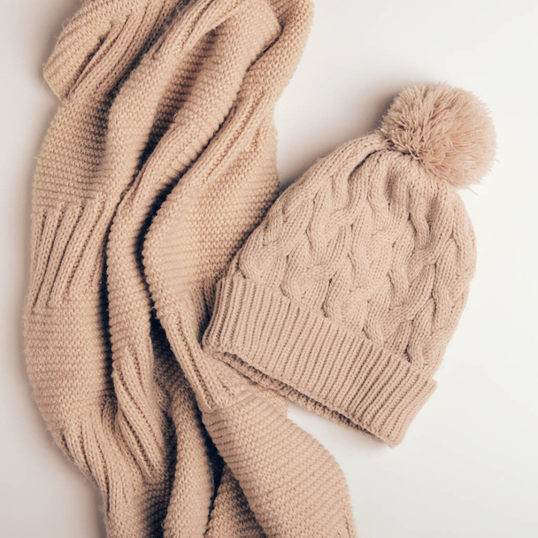 Sciarpa lavorata a maglia un tubo o un colletto da fili caldi e berretto beige con un pompon. Vestiti per l'autunno e l'inverno. primo piano
 - Foto, immagini