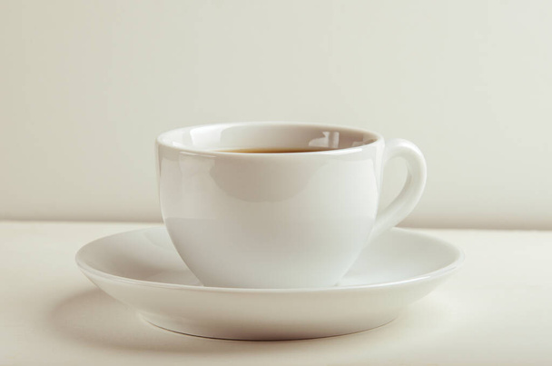 Mug with warm tea on a white table on white background. - Фото, зображення