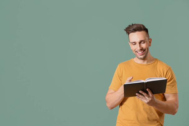 Happy man reading book on color background - Photo, Image