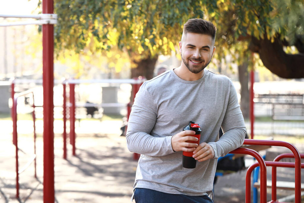 Sporty man with protein shake outdoors - Photo, Image