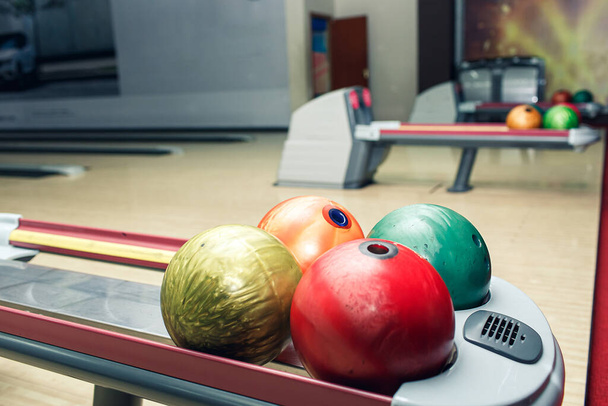 різнокольорові кульки для боулінгу лежать на полиці в клубі боулінгу
. - Фото, зображення