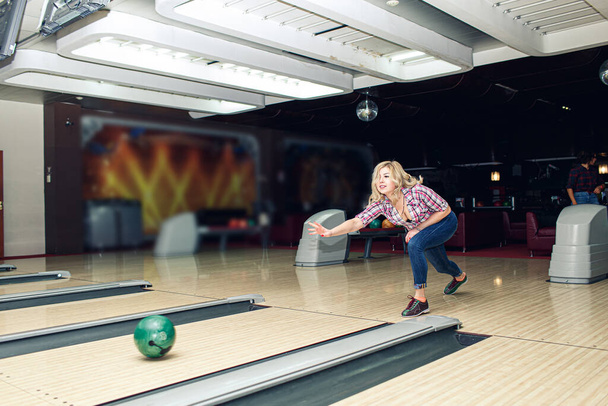 beautiful blonde girl plays bowling in club. - Фото, изображение