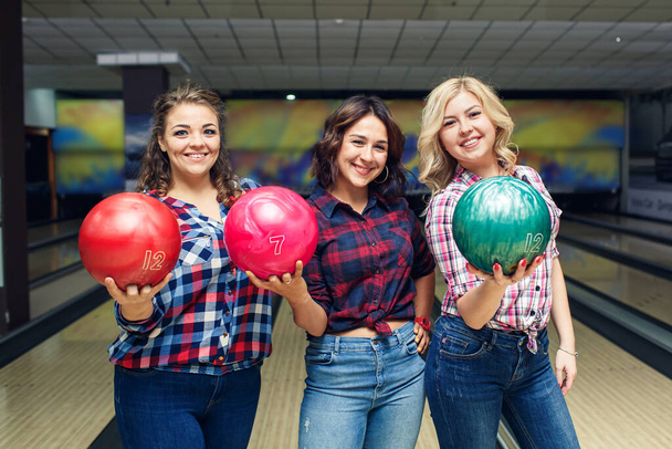 Três divertidas namoradas atraentes segurar bolas de boliche e olhar para você
. - Foto, Imagem