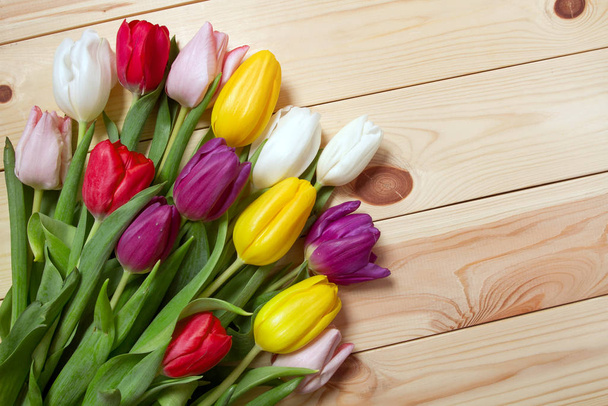 Egy csokor színes tulipán a padlón. Ajándék egy női napnak. Tavaszi tulipán virágok háttér - Fotó, kép