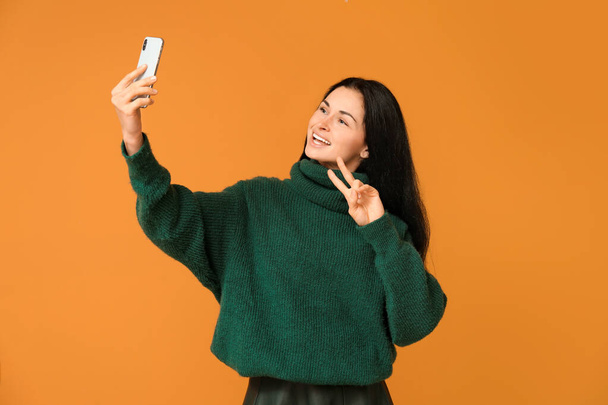 Beautiful young woman taking selfie on color background - Zdjęcie, obraz