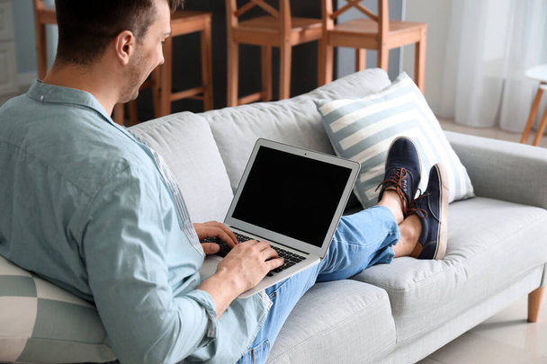 Nuori mies kannettavan tietokoneen kanssa chattailu kotona
 - Valokuva, kuva