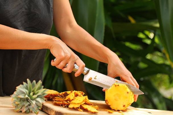 fresh ripe pineapple slicing girl hands on a wooden table in a tropical garden  sri lanka - Foto, afbeelding
