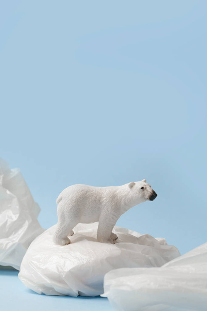 White polar bear on plastic bag on blue background, plastic pollution and climate change concept - Foto, imagen