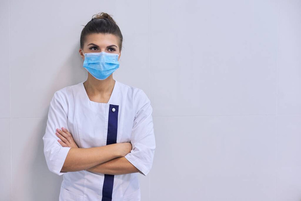 Young serious confident woman doctor in medical mask with folded arms - Φωτογραφία, εικόνα