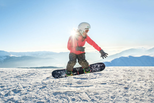 Pretty young woman on the snowboard jumping over the slope in winter - 写真・画像