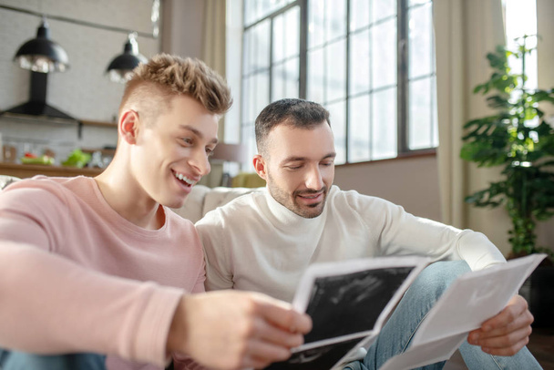 Two happy young men looking at pictures of ultrasound. - Foto, Bild