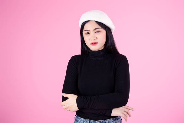 Crossed arms Asian woman wearing black sweater on pink background, lifestyle concept. - Foto, Bild