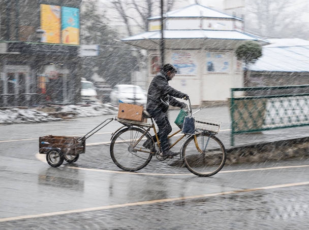 Ciclista en la carretera de la ciudad en un día lluvioso en movimiento borroso. Imagen desenfocada - Foto, Imagen