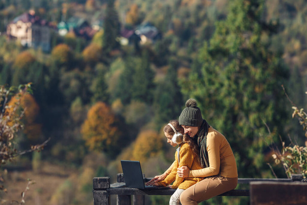 anya és lánya dolgozik laptop kívül teraszon ősszel - Fotó, kép