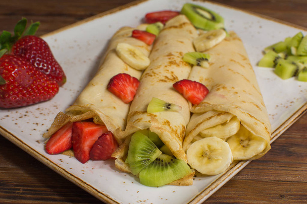Terveellisiä ohukaisia hedelmiä, banaania, kiiviä ja mansikkaa. Terveellinen ranskalainen aamiainen
 - Valokuva, kuva