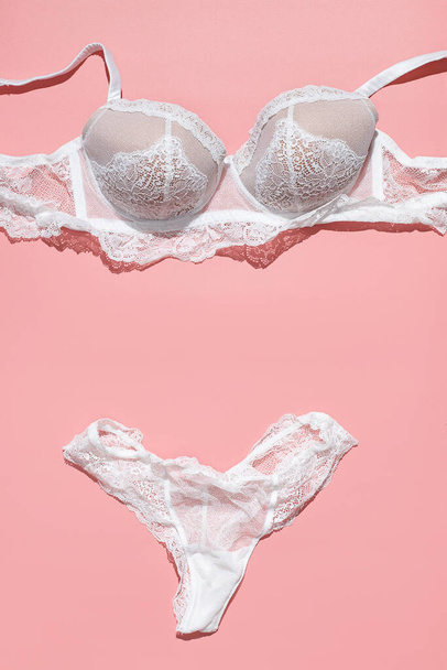 Sexy white lace bra and panties on pink background. Stylish lingerie flat lay. Underwear fashion concept - Foto, immagini