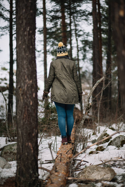 Back of a girl standing on fallen tree - Foto, imagen
