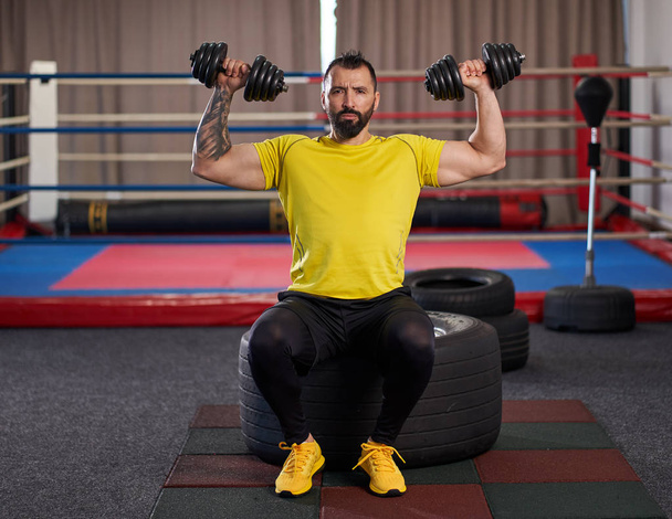 Man exercising with dumbbells in a gym - Фото, изображение