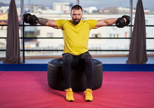 Athletic man doing dumbbell exercises in the gym - Fotografie, Obrázek