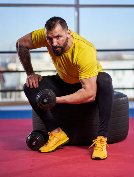 Man exercising with dumbbells in a gym - Fotó, kép