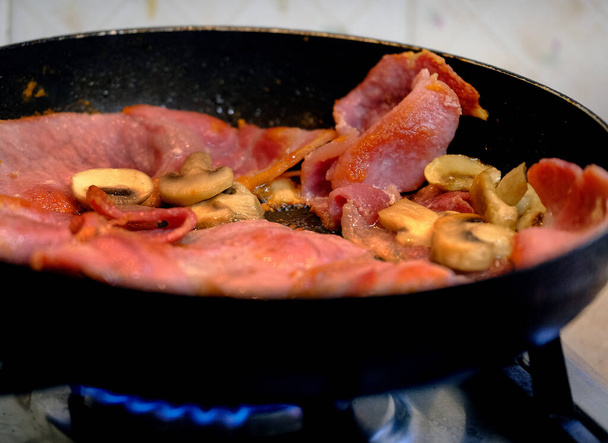 Cozimento de bacon e cogumelos na frigideira em casa fogão a gás de cozinha. - Foto, Imagem