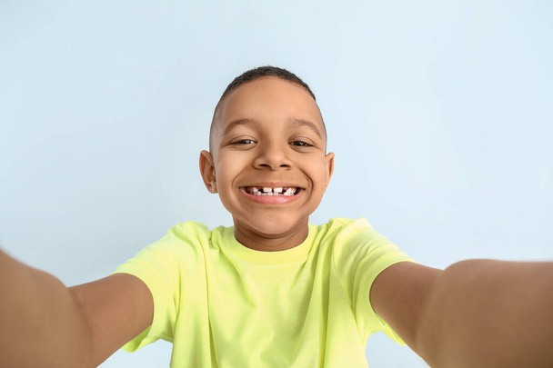 Glücklicher afroamerikanischer Junge macht Selfie auf farbigem Hintergrund - Foto, Bild