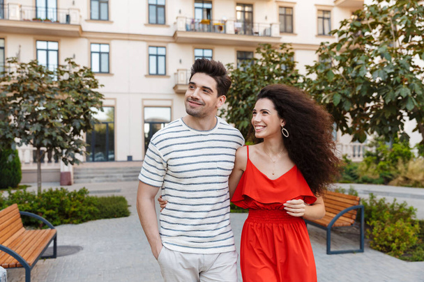 Image of happy caucasian couple in casual clothes smiling and hugging while walking on city street - Fotó, kép