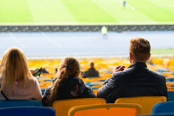 Parents et enfants regardent tout en profitant d'un jeu de sièges pour les spectateurs au stade
 - Photo, image